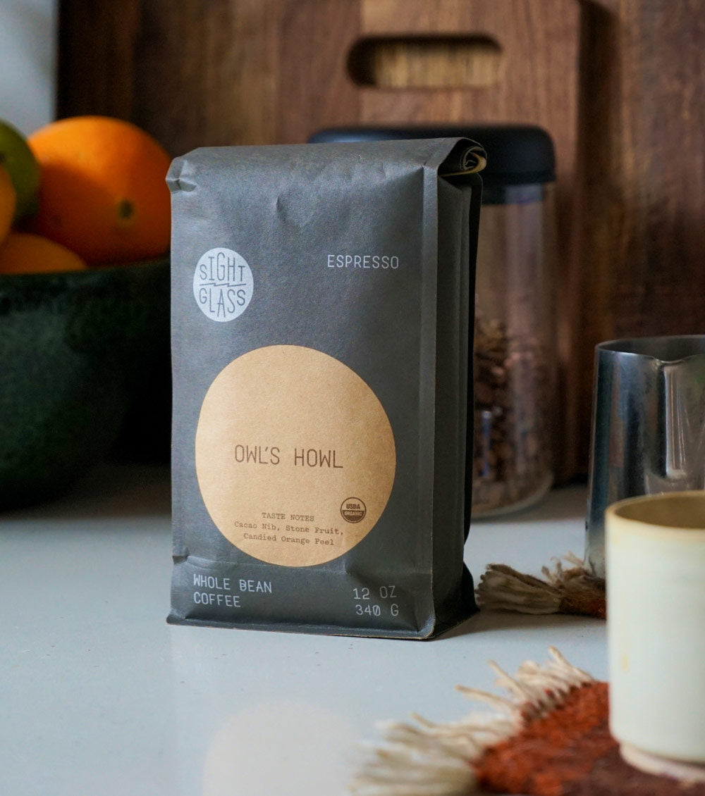 Sightglass's Owl's Howl Coffee bag on a table with a bowl of oranges and a jar in the background.