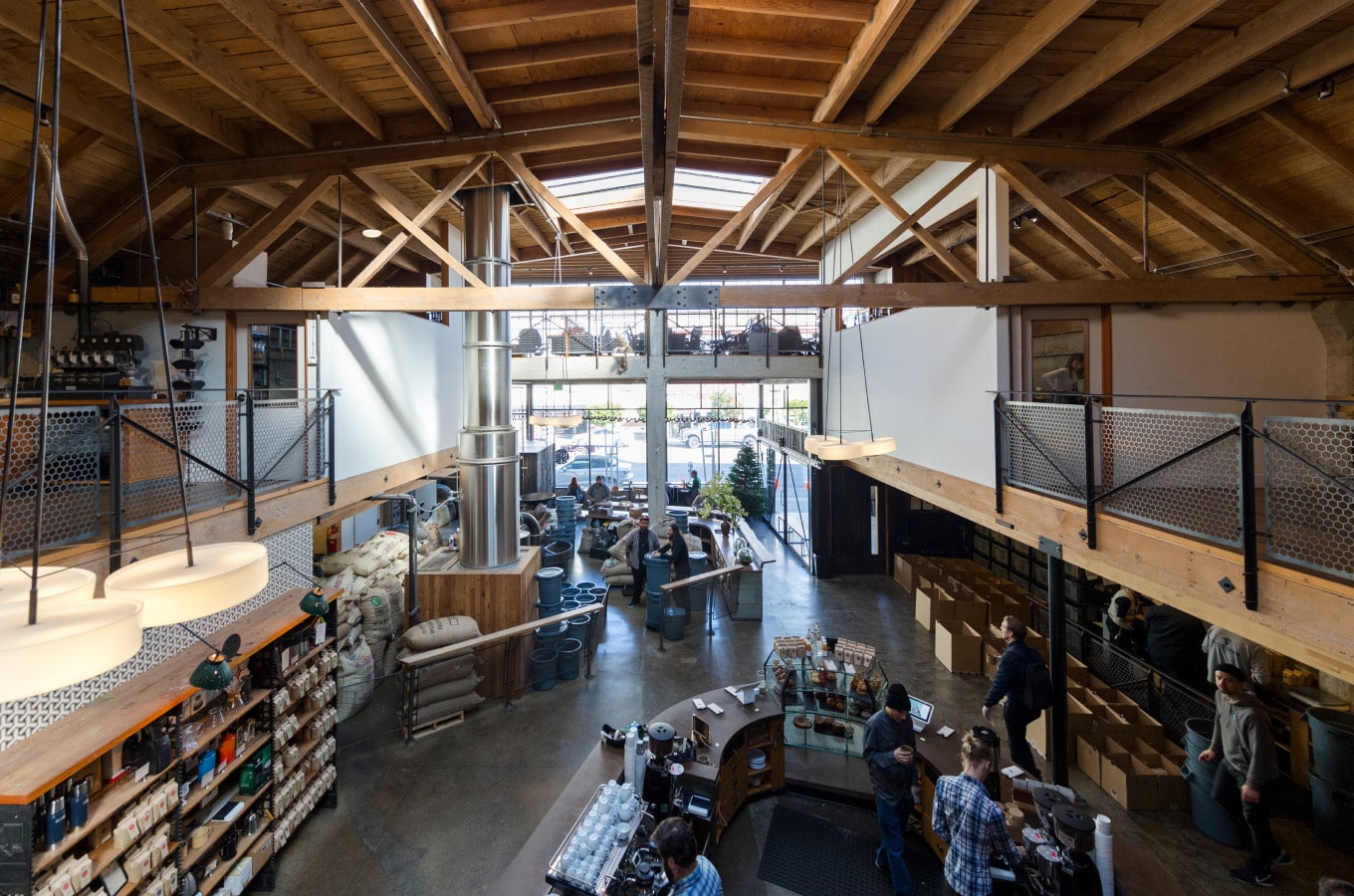 Sightglass Coffee's SoMa location in San Francisco main view of the space with the counter downstairs, the roasting machine in the background, and a view on the street,