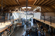 Sightglass Coffee's SoMa location in San Francisco main view of the space with the counter downstairs, the roasting machine in the background, and a view on the street,